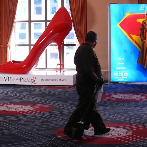 A maintenance worker walks past advertisements for the upcoming films "The Devil Wears Prada," left, and "Supergirl" during the opening day of CinemaCon 2026, the official convention of Cinema United, on Monday, April 13, 2026, at Caesars Palace in Las Vegas. (AP Photo/Chris Pizzello)