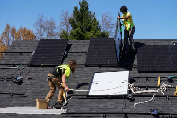 FILE - Theodore Tanczuk, left, and Brayan Santos, right, of solar installer YellowLite, put panels on the roof of a home in Lakewood, Ohio, April 16, 2025. (AP Photo/Sue Ogrocki, File)