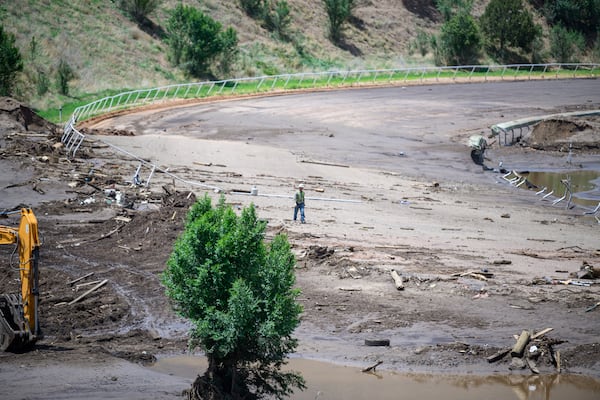 A man crosses the Ruidoso Downs Racetrack which was partially destroyed after the flood, Wednesday, July 9, 2025, in Ruidoso, N.M. (AP Photo/Roberto E. Rosales)
