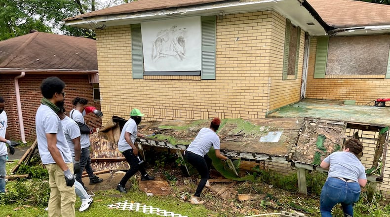 A crew from the group HEY! pulls down the rotten wooden ramp leading to the home of Kathryn Johnston, who was killed there by police in 2006. Photo by Bill Torpy