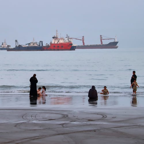 People spend time at a beach as commercial vessels are anchored in the Strait of Hormuz off Bandar Abbas, Iran, Wednesday, Aug. 5, 2026. (Amirhosein Khorgooi/ISNA via AP)
