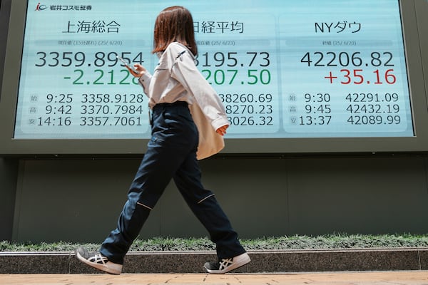 A person walks in front of an electronic stock board showing Shanghai, Japan's Nikkei and NY Dow indexes at a securities firm Monday, June 23, 2025, in Tokyo. (AP Photo/Eugene Hoshiko)