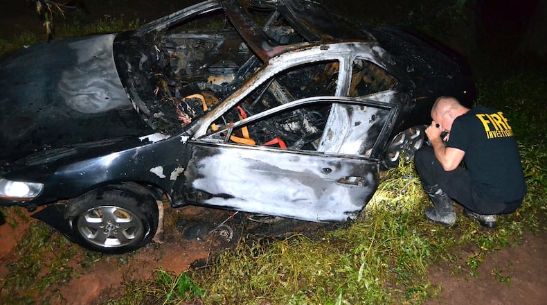 A fire investigator examines a car involved in a fiery crash late Wednesday. (Tim Cavender/Cherokee County fire department)