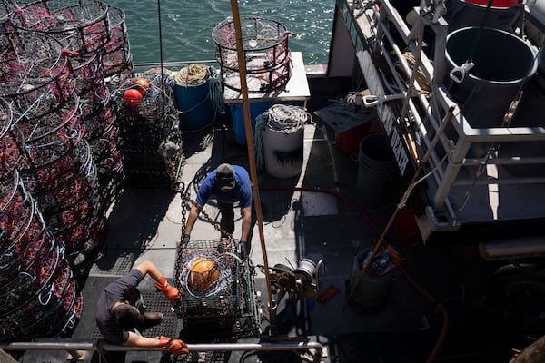 Hunter Nguyen, top, and Jonathan Tin, load pop-up gear that prevents whale entanglements onto the boat Pale Horse at Pier 45 in San Francisco, Thursday, April 10, 2025. (AP Photo/Emily Steinberger)