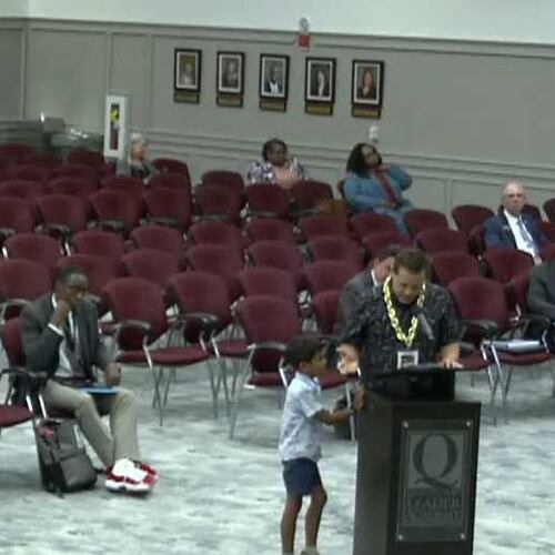 Gwinnett County parent Jeramie Cavallaro, standing at the lectern, with his son, Jackson, 7, spoke at the Aug. 21, 2025 school board meeting in support of weapons detection systems at its elementary schools. (Photo Credit: Gwinnett County Public Schools)
