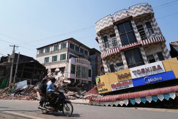 A local man drives a motorbike past a damaged building, in the aftermath of an earthquake, in Naypyitaw, Myanmar, Sunday, March 30, 2025. (AP Photo/Aung Shine Oo)