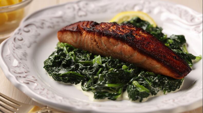 Crispy salmon with creamed greens, punctuated with lemon, pepper and garlic, is a bolder version of an ’80s dish. (Joan Moravek/Food Styling) (E. Jason Wambsgans/Chicago Tribune/TNS)