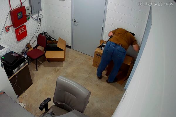 FILE - This image from a security camera footage provided by the Cullman County Sheriff's Office shows an individual who works at there sticks his head and upper body in the hole, attempting to open the door to the evidence room, at the Hanceville Police Department in Hanceville, Ala. (Cullman County Sheriff's Office via AP, File)