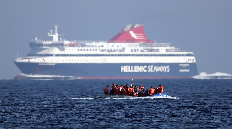 A migrant boat passes a passenger ferry as it makes the crossing from Turkey to the Greek island of Lesbos on November 14, 2015 in Sikaminias, Greece. Rafts and boats continue to make the journey from Turkey to Lesbos each day as thousands flee conflict in Iraq, Syria, Afghanistan and other countries. (Carl Court/Getty Images)