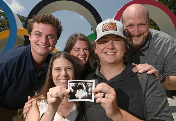 The Leo family: Brooke (front left) and husband, AJC reporter Jack, pose with a sonogram of their daughter, expected to arrive later this year. Back row: Max (Jack's brother) and parents Heather and Steve round out the picture at Centennial Olympic Park. (Hyosub Shin/AJC)