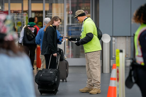 Rafael Naveira, a member of the air traffic controllers union and a controller in Peachtree City, hands out leaflets explaining the effects of the federal government shutdown to travelers at Hartsfield-Jackson Atlanta International Airport on Tuesday, Oct. 28, 2025. (Ben Hendren for the AJC)
