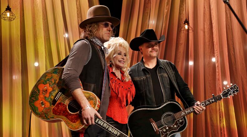 Dolly Parton poses for a picture with Kenny Alphin, left, and John Rich, right, of the country music duo Big & Rich, during tapings for Parton's Smoky Mountain Rise Telethon Tuesday, Dec. 13, 2016, in Nashville, Tenn. Parton has lined up an all-star list of performers for a three-hour telethon to raise money for thousands of people whose homes were damaged or destroyed in Tennessee wildfires. (AP Photo/Mark Humphrey)