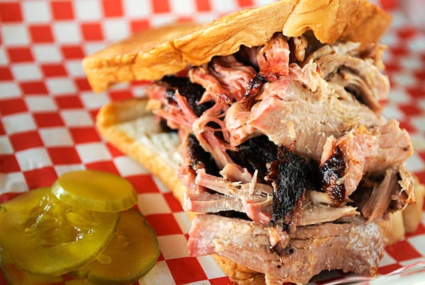 Shreds of tender pork are piled high on thick slices of Texas toast, accompanied by a few slices of dill pickles at Community BBQ.