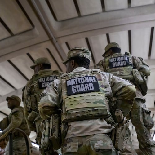 Members of the Arkansas National Guard continue their patrol after carrying an elderly woman in her wheelchair down the steps to the train platform due to an out-of-service elevator at the Columbia Heights metro station, Monday, Aug. 10, 2026, in Washington. (AP Photo/Rod Lamkey, Jr.)