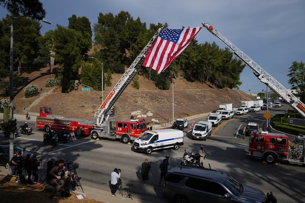Medical examiner vans are driven along a procession route near where an explosion at a training facility killed three sheriff's deputies on Friday, July 18, 2025, in Los Angeles. (AP Photo/Eric Thayer)