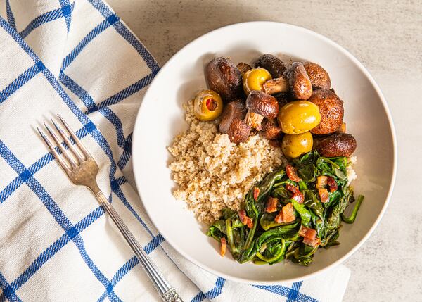 This hearty, savory breakfast bowl is made using recipes for Tahini Bulgur Wheat; Roasted Mushrooms & Spanish Olives; and Sauteed Spinach & Bacon. (Aaliyah Man for The Atlanta Journal-Constitution / food styling by Jennifer Hill Booker)