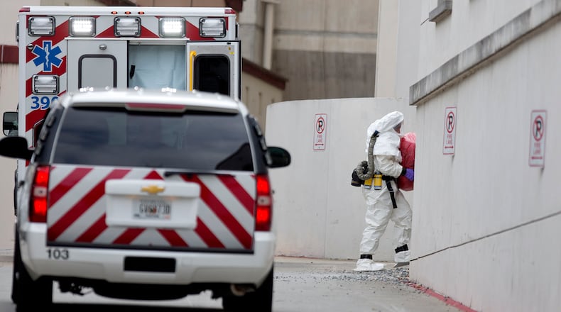 A person wearing a haz-mat suit carries a wrapped object out of an ambulance into Emory University Hospital after an ebola patient was taken in for treatment, Tuesday, Sept. 9, 2014, in Atlanta. The fourth American aid worker sickened with the Ebola virus arrived Tuesday morning for treatment at Emory University Hospital, where two others have been successfully treated. (AP Photo/David Goldman)