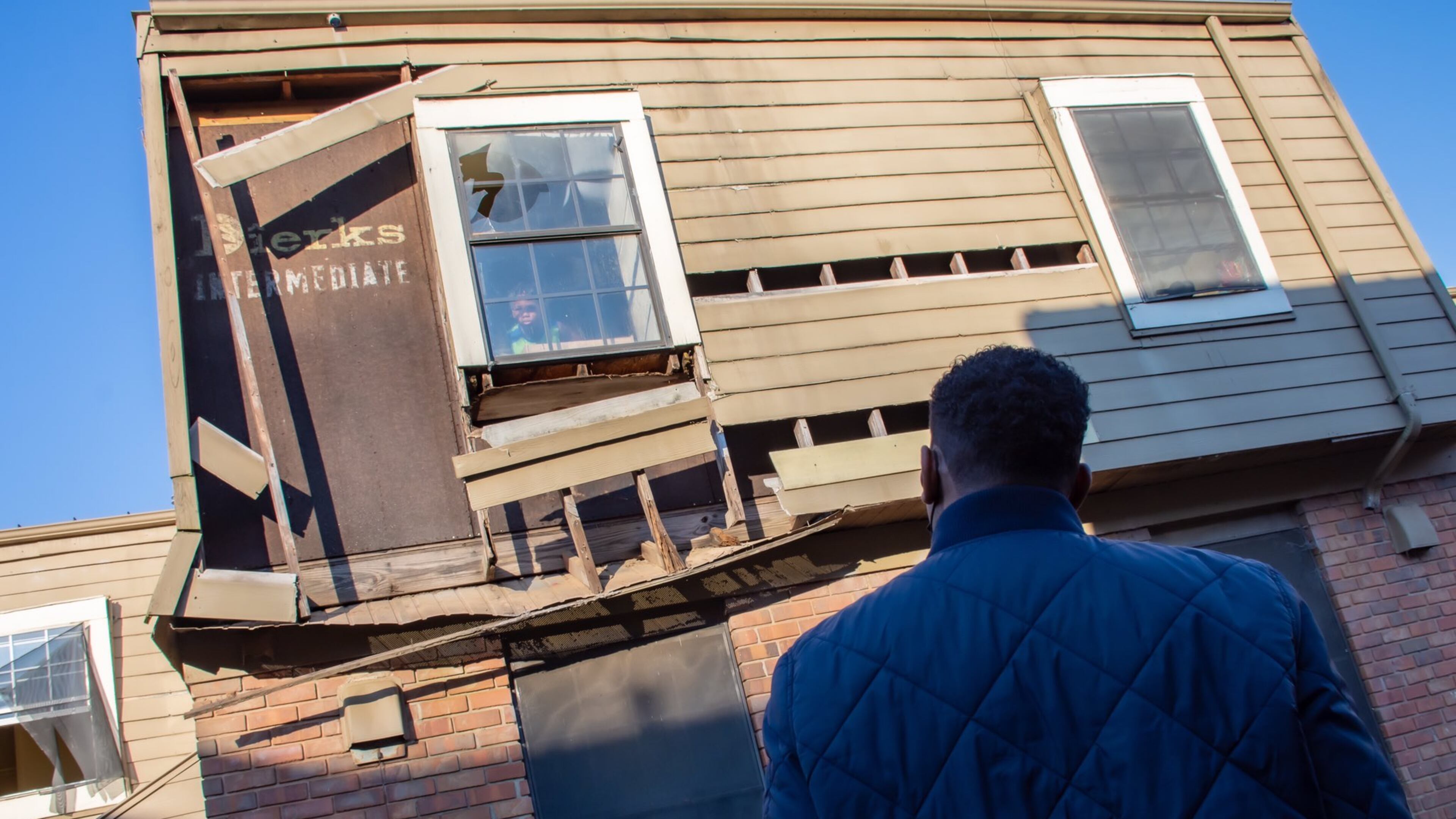 A child stares out of a near-collapsing window at Atlanta Mayor Andre Dickens as he reviews conditions at the Forest Cove Apartments in the Thomasville Heights community. (Courtesy of City of Atlanta 2022)