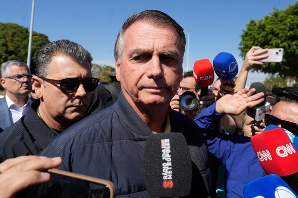 Brazil's former President Jair Bolsonaro speaks to the press outside the Secretariat of Penitentiary Administration where he arrived after the Supreme Court ordered him to be fitted with an electronic ankle monitor in Brasilia, Brazil, Friday, July 18, 2025. (AP Photo/Eraldo Peres)