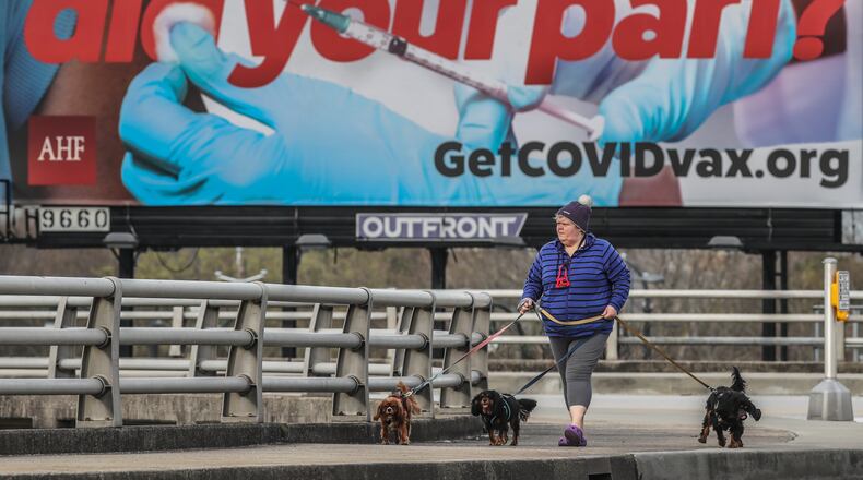 March 10, 2021 Atlanta: Billboards getting the message out about vaccines to combat the COVI-19 pandemic are up throughout the metro Atlanta area. Here Kerstin Johnson walked her dogs along Martin Luther King Jr. Drive at Centennial Olympic Park Drive in downtown Atlanta on Thursday March 11, 2021. Johnson said up to this point she had been “Too young” to get a vaccine. She said she’s looking forward to it. Georgians as young as 55 and others with high-risk medical conditions will be eligible to receive the coronavirus vaccine under plans announced Wednesday by Gov. Brian Kemp. An additional 3.3 million Georgians will be eligible for the vaccines starting Monday. The list of high-risk conditions will likely make the vast majority of Georgia adults qualified to get the shots such as those with cancer, heart conditions and diabetes, high blood pressure, pregnancy and asthma. Kemp also said he hopes to expand vaccine eligibility to all adults by early April. In the latest move, President Joe Biden announced Wednesday the federal government will purchase an additional 100 million doses of the one-shot Johnson & Johnson vaccine. (John Spink / John.Spink@ajc.com)