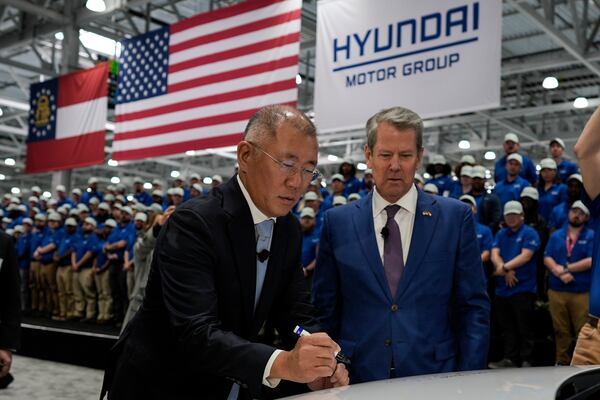 Euisun Chung, Executive Chair, Hyundai Motor Company, left, stands with Georgia Gov. Brian Kemp as Chung signs an IONIQ 9 EV vehicle during a media tour and grand opening at the Hyundai Motor Group Metaplant America, Wednesday, March 26, 2025, in Ellabell, Ga. (AP Photo/Mike Stewart)