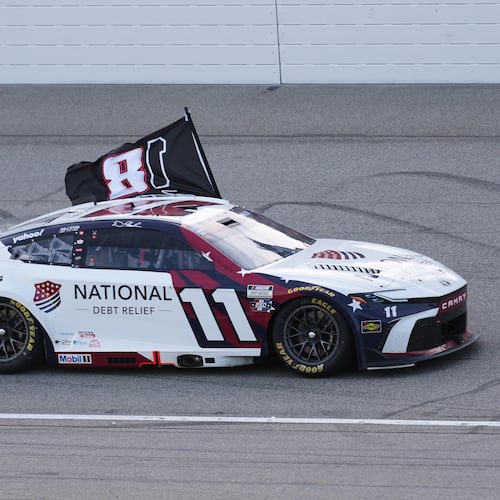 Denny Hamlin celebrates winning while honoring Kyle Busch with a flag after a NASCAR Cup Series auto race at Michigan International Speedway in Brooklyn, Mich., Sunday, June 7, 2026. (AP Photo/Paul Sancya)