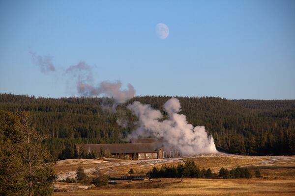 Old Faithful is seen erupting from a distance as the moon rises over the Upper Geyser Basin at Yellowstone National Park, Mont., Sept. 25, 2023. (AP Photo/Hannah Schoenbaum)