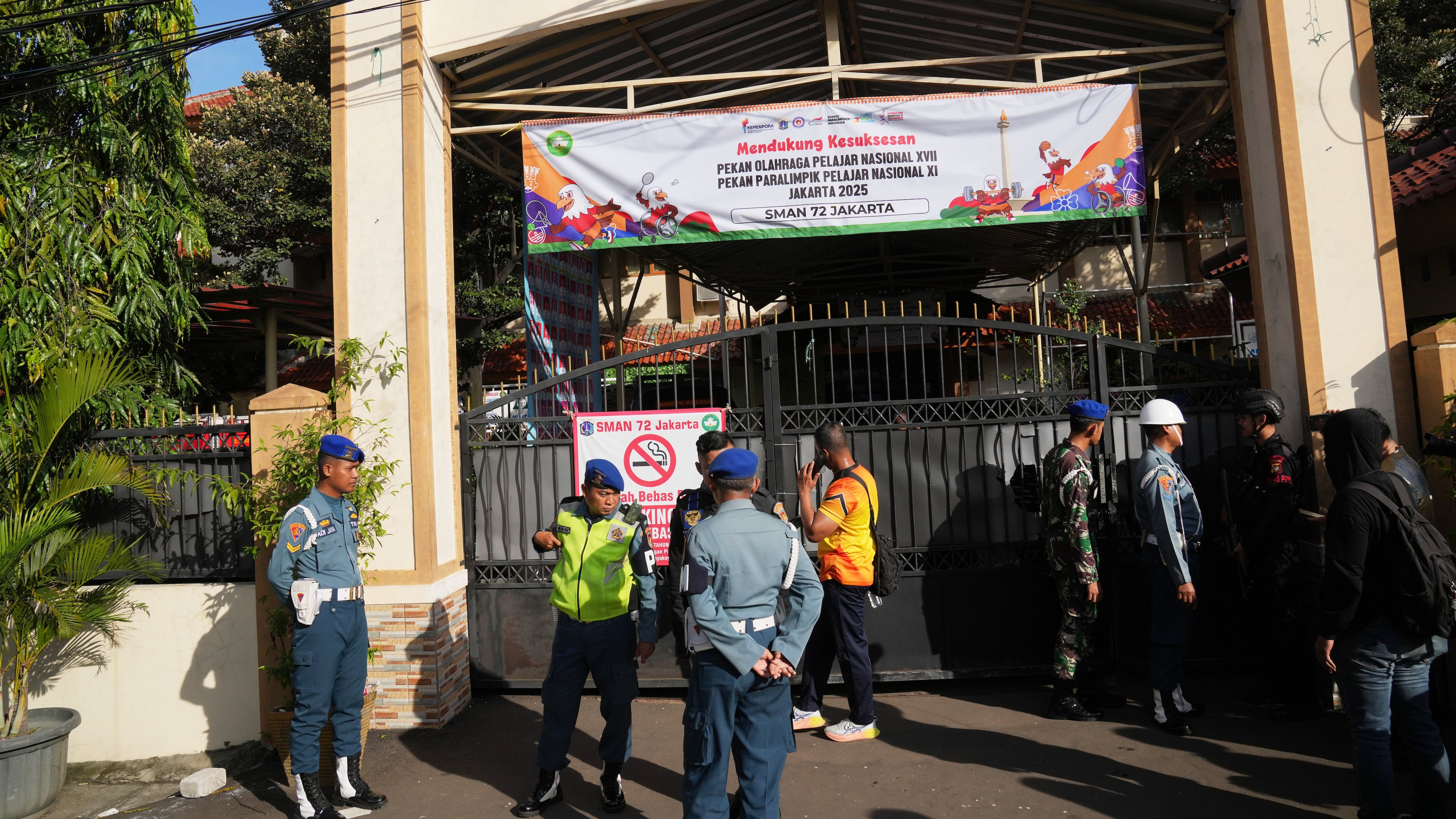 Police officers and military personnel stand guard at the gate of a school where explosions reportedly occurred, in Jakarta, Indonesia, Friday, Nov. 7, 2025. (AP Photo/Dita Alangkara)