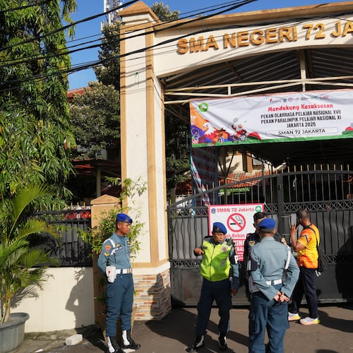 Police officers and military personnel stand guard at the gate of a school where explosions reportedly occurred, in Jakarta, Indonesia, Friday, Nov. 7, 2025. (AP Photo/Dita Alangkara)