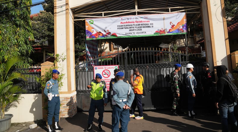 Police officers and military personnel stand guard at the gate of a school where explosions reportedly occurred, in Jakarta, Indonesia, Friday, Nov. 7, 2025. (AP Photo/Dita Alangkara)