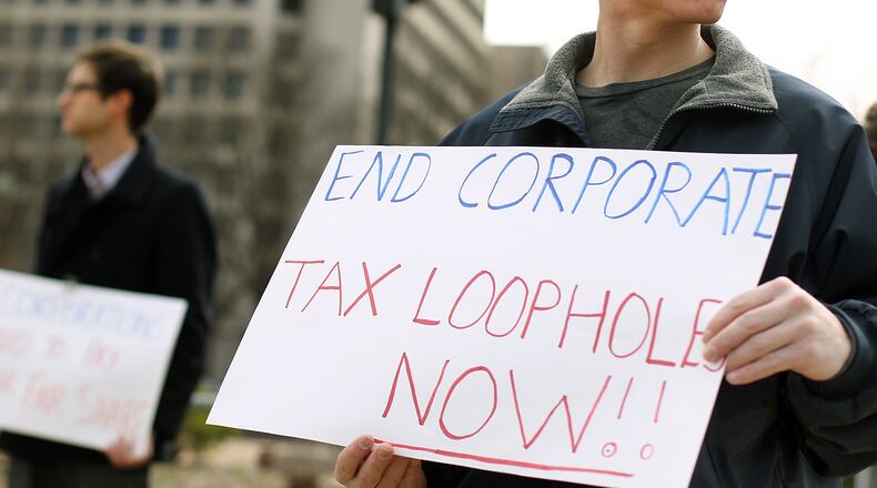 A Georgia Fair Share intern holds a sign protesting corporate tax loopholes during a Georgia Fair Share rally near the Coca-Cola headquarters on North Avenue.