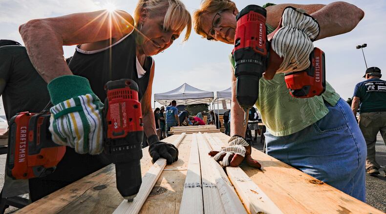 FILE - Volunteers Susan Chastain and Jenny Allen drill holes into two-by-fours during Bunks Across America, a non-profit event to build bunk beds for children in need at Lowe's, June 12, 2021 in East Brainerd, Tenn. (Troy Stolt/Chattanooga Times Free Press via AP, File)