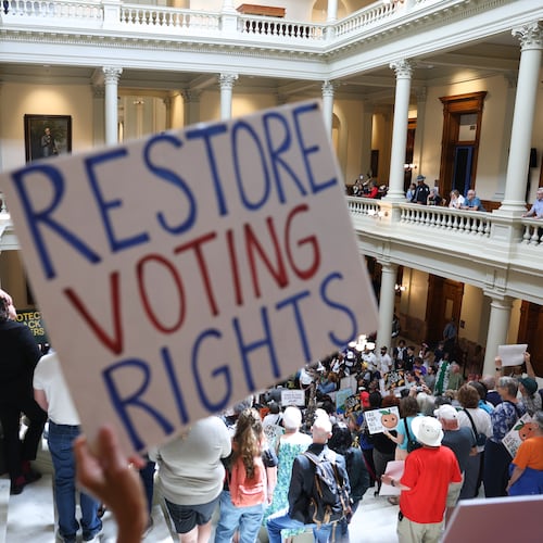 An activist holds a "Restore Voting Rights" sign at a news conference before the state Legislature convenes for a special session at the Capitol on Wednesday. (Arvin Temkar/AJC)