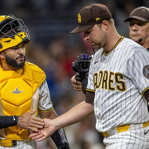 San Diego Padres catcher Rodolfo Durán, left, gives a hand to starting pitcher Michael King, front right, after the in the sixth inning of a baseball game against the Los Angeles Dodgers, Monday, May 18, 2026, in San Diego. (AP Photo/Tony Ding)