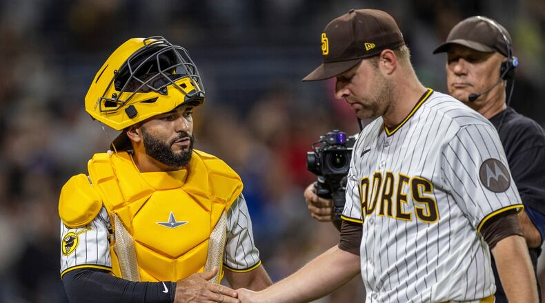 San Diego Padres catcher Rodolfo Durán, left, gives a hand to starting pitcher Michael King, front right, after the in the sixth inning of a baseball game against the Los Angeles Dodgers, Monday, May 18, 2026, in San Diego. (AP Photo/Tony Ding)