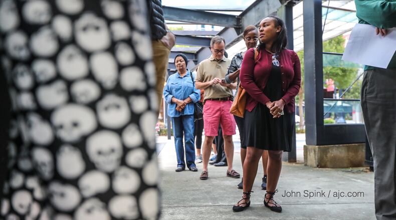 Behind the Halloween skull pants of a voter, Brennan Sears-Collins (center) and others wait to vote at Buckhead Library