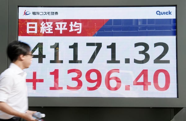 A person walks in front of an electronic stock board showing Japan's Nikkei index at a securities firm Wednesday, July 23, 2025, in Tokyo. (Kyodo News via AP)