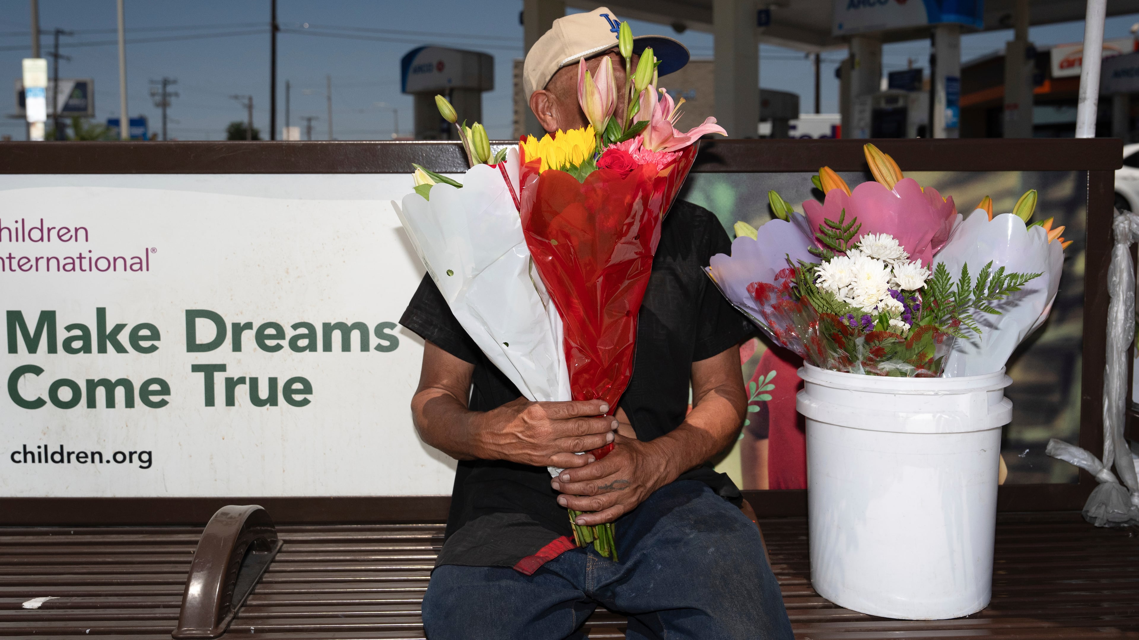 FILE - Flower vendor Jose, an immigrant from Mexico, sits for a photo with his face covered by flowers outside a gas station in Los Angeles, Friday, Aug. 8, 2025. (AP Photo/Jae C. Hong, File)