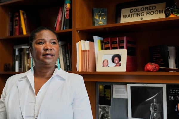 Tanya Washington, a professor of law at Georgia State University, poses for a portrait in her office near a framed photo of her wearing her hair in an afro, Tuesday, May 6, 2025, in Atlanta. (AP Photo/Stephanie Scarbrough)