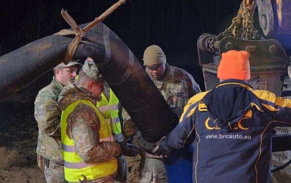 In this image provided by the U.S. Army, U.S. Army soldiers from the 1st Armored Brigade Combat Team, 3rd Infantry Division, along with Lithuanian Army and emergency services personnel, assemble a water pump during recovery efforts for four U.S. soldiers in a U.S. Army M88 Hercules submerged under several meters of water in a swamp near a training area near Pabadre, Lithuania, Thursday, March 27, 2025. (Christopher Saunders/U.S. Army via AP)