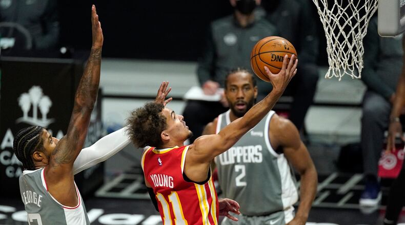 Trae Young drives to the basket as Paul George defends and Kawhi Leonard looks on during Monday's Hawks-Clippers game in Los Angeles.