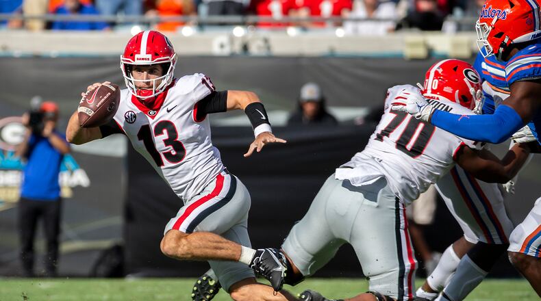 Georgia quarterback Stetson Bennett (13) scrabbles out of the pocket during the first half of an college football game against Florida, Saturday, Oct. 30, 2021, in Jacksonville, Fla. (Stephen B. Morton/Atlanta Journal-Constitution)