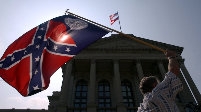 030508-ATLANTA-Elijah Coleman (cq), with the Sons of Confederate Veterans, waves the post-'56 flag with the Confederate battle emblem in protest Thursday afternoon just after the new Georgia flag was raised over the state Capitol. About a dozen protesters were on the Capitol steps as the new flag went up. (BEN GRAY/STAFF)