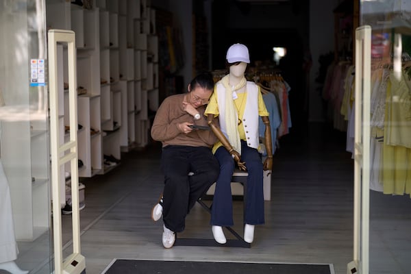 A vendor sit at her shop, during a major power outage in Barcelona, Spain, Monday, April 28, 2025. (AP Photo/Emilio Morenatti)