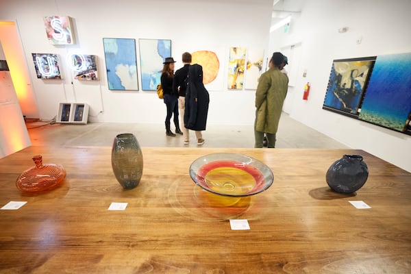 Guests engage with the artwork at “Love Asheville from Afar” during its opening at the Ponce City Market on Thursday, Dec. 5, 2024. This exhibit aims to support Asheville artists affected by Hurricane Helene. It will be on display through Dec. 29. (Miguel Martinez/AJC)