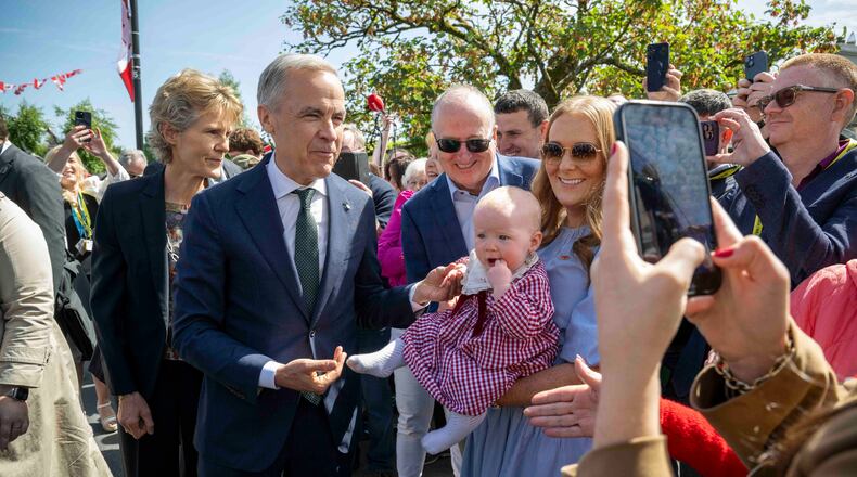 Canadian Prime Minister Mark Carney, front left, has a picture taken with Lily Meskil, 9 months and her grandfather Ger Basquel and mother Rachel Basquel, during a visit to Aughagower, Ireland, Sunday, June 14, 2026. (Andrew Downes/PA via AP)