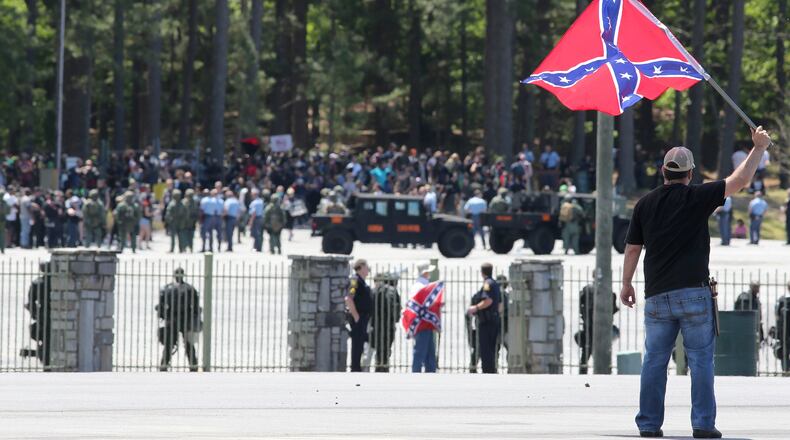 Joseph Andrews, one of a small group with the Rock Stone Mountain rally, waves a confederate battle flag towards a mass of counter-protesters more than 100 yards away at Stone Mountain Park on Saturday afternoon April 23, 2016 where a white power protest and two counter protests were scheduled. Ben Gray, bgray@ajc.com