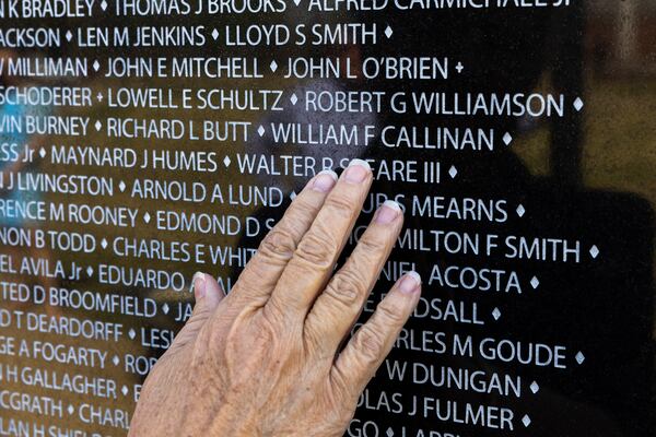 Margo Truett touches the name of her father, Army Maj. William Callinan, on a replica of the Vietnam War Memorial wall at the National Infantry Museum in Columbus on Thursday, March 21, 2024. (Arvin Temkar / arvin.temkar@ajc.com)