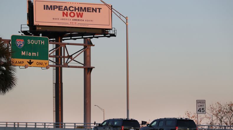 Vehicles from the motorcade carrying President Donald Trump pass a billboard reading: 'Impeachment Now Make America America Again!' as he is driven to Mar-A-Lago on March 23, 2018 in West Palm Beach, Fla. (Photo by Joe Raedle/Getty Images)