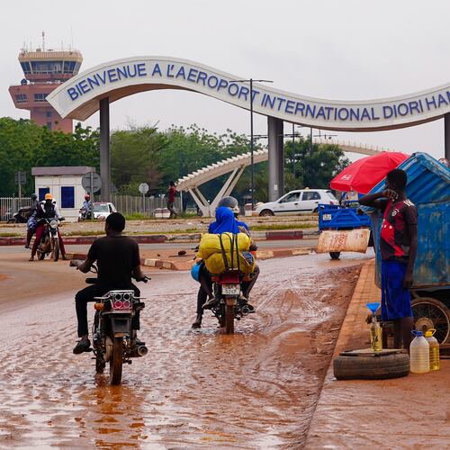 FILE- Motorcyclists ride by the entrance of the airport in Niamey, Niger, Tuesday, Aug. 8, 2023. (AP Photo/Sam Mednick, File)